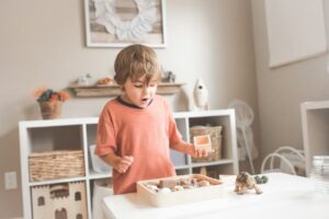 A photograph of a child playing with blocks in a neutral-colored playroom.